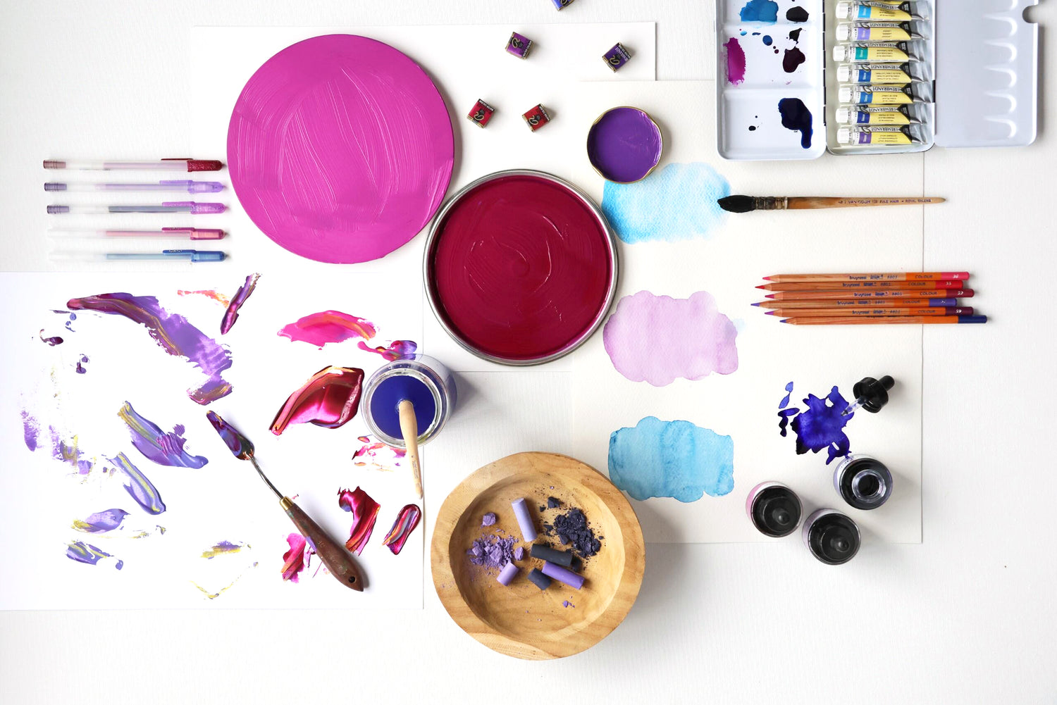 Art supplies including paint, brushes, and palettes on a white surface